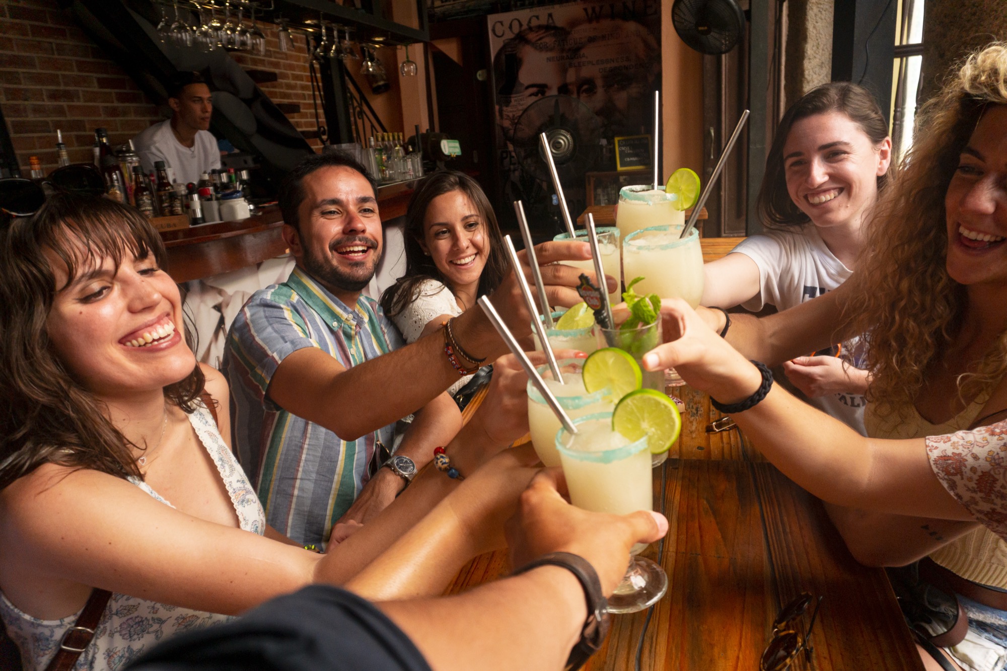 A long table of friends reaching in to clink drinks on a string-lit Havana patio at night