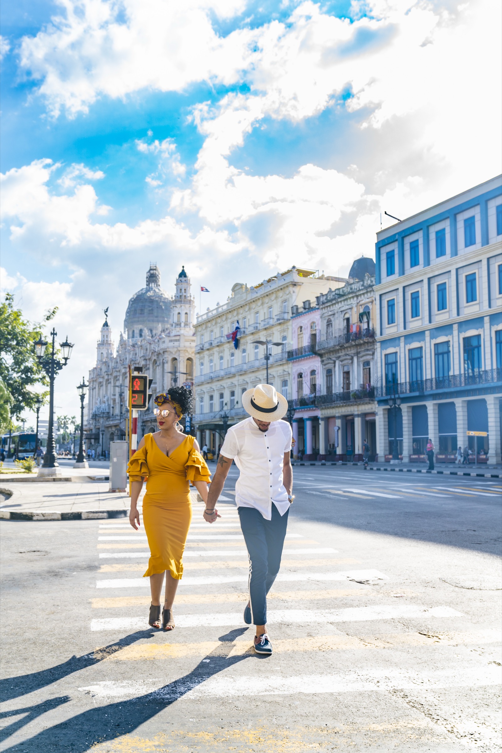A couple crossing the street under a dramatic sky