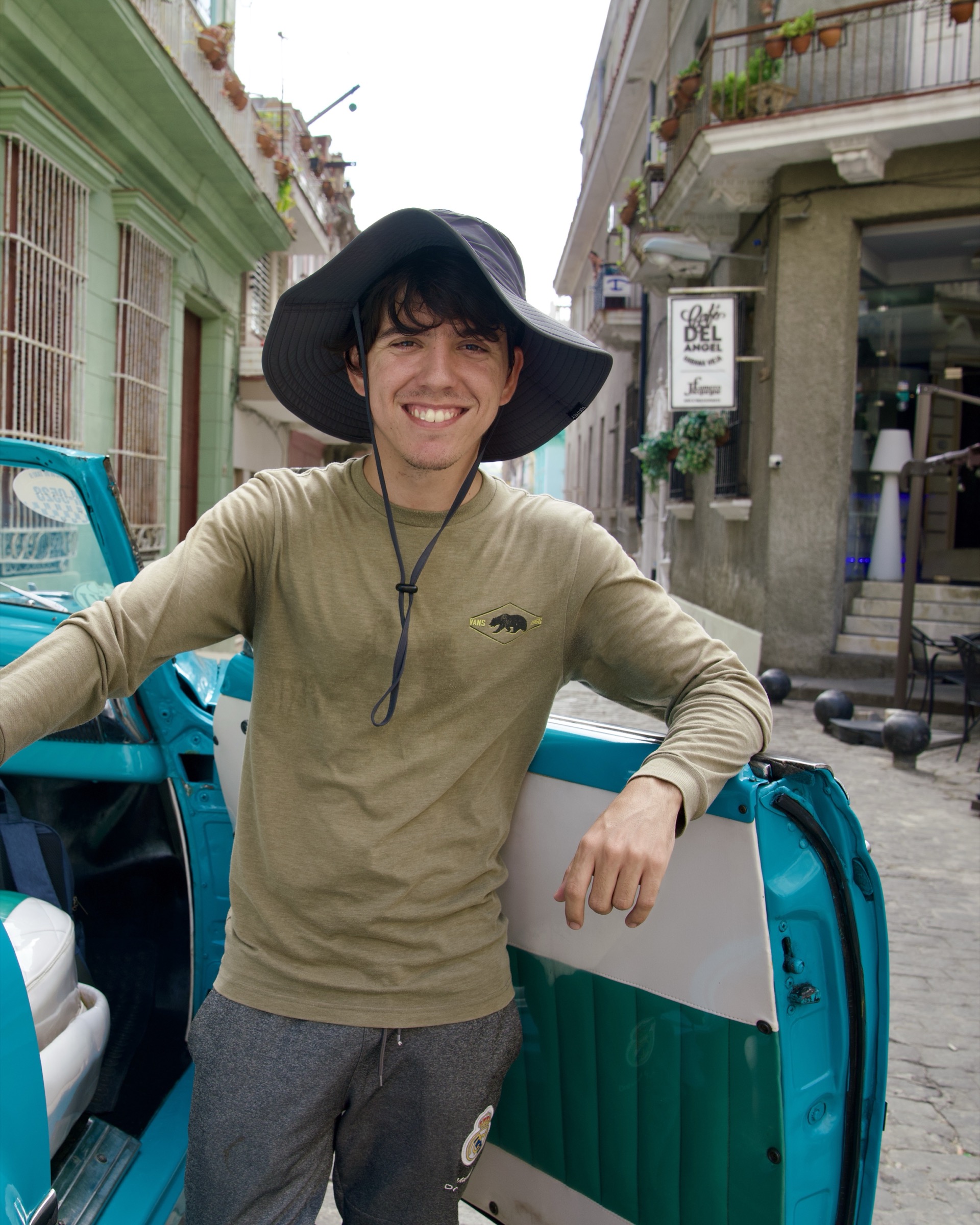 Manuel standing beside a turquoise classic convertible in Old Havana
