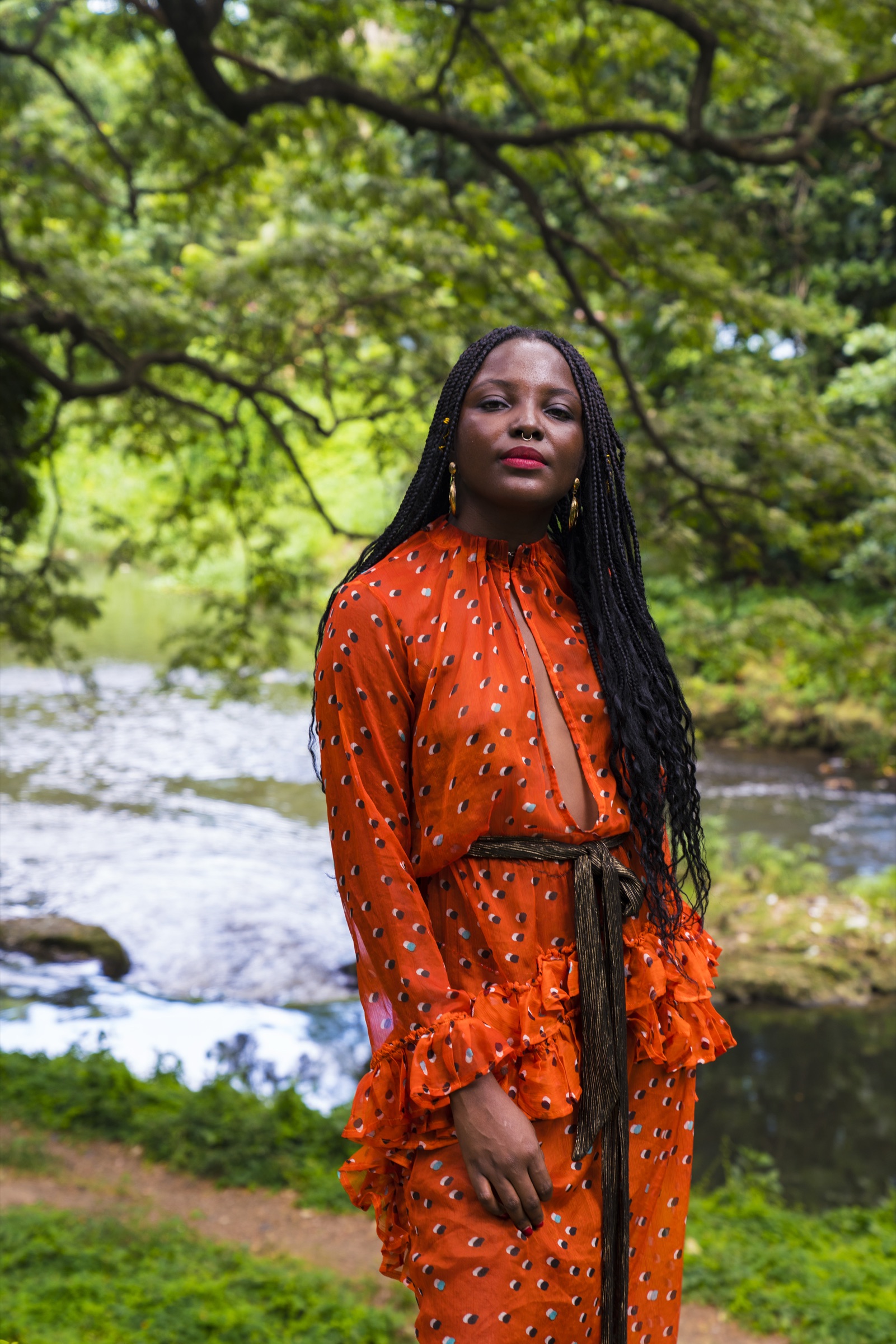 A woman in an orange dress standing above the rapids of the Almendares river