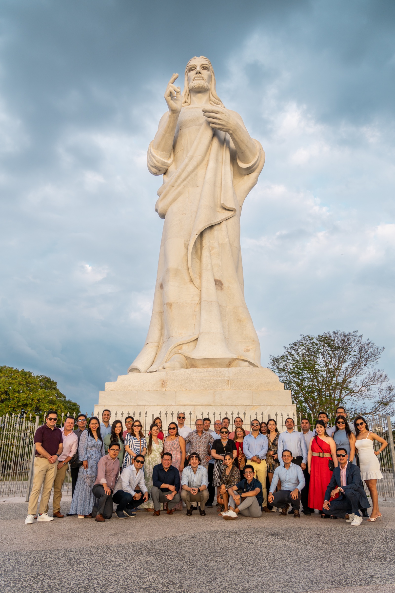 A large group posing together in front of the Christ of Havana statue