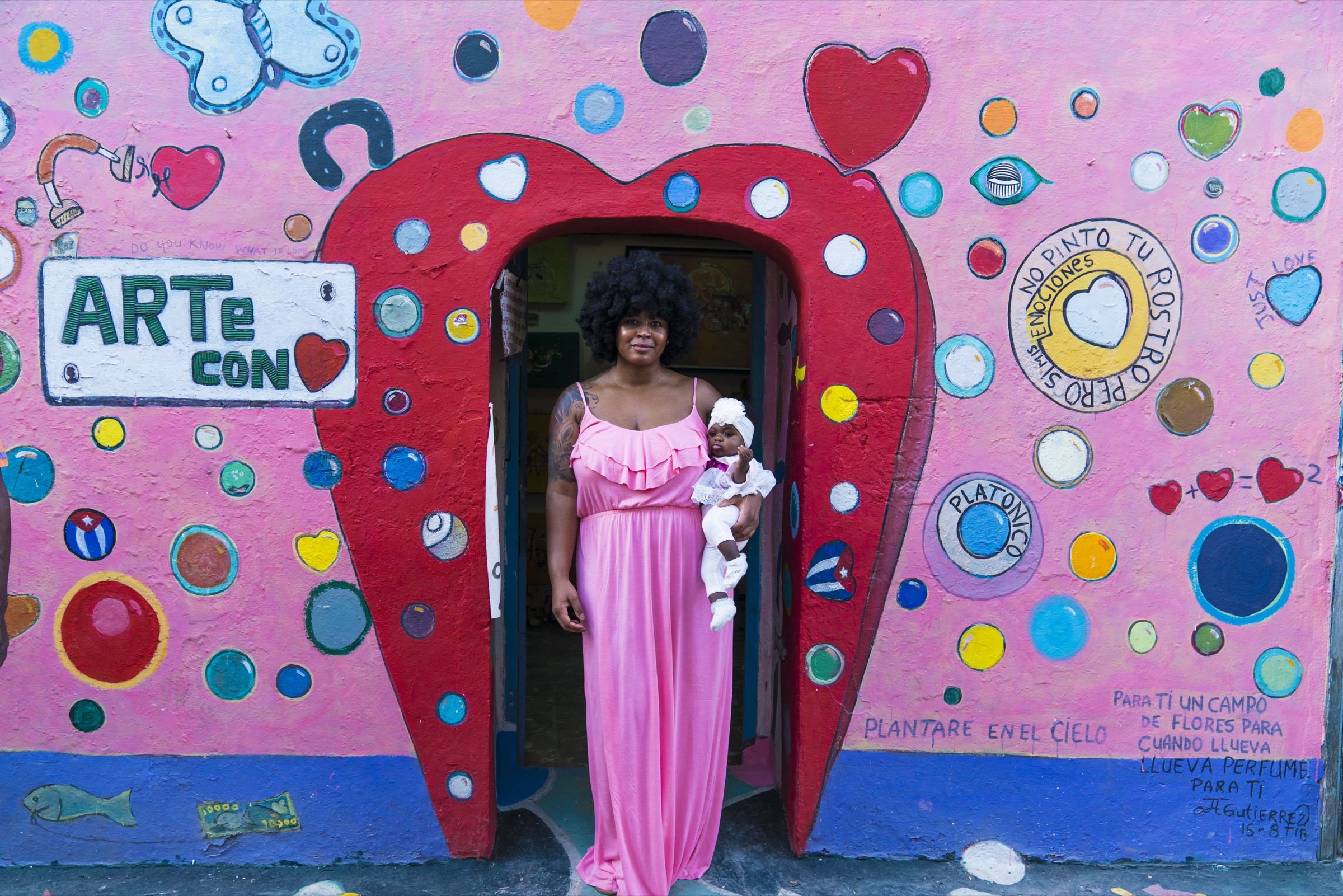 A woman in a pink dress in the heart-shaped doorway of the Arte con Corazón gallery