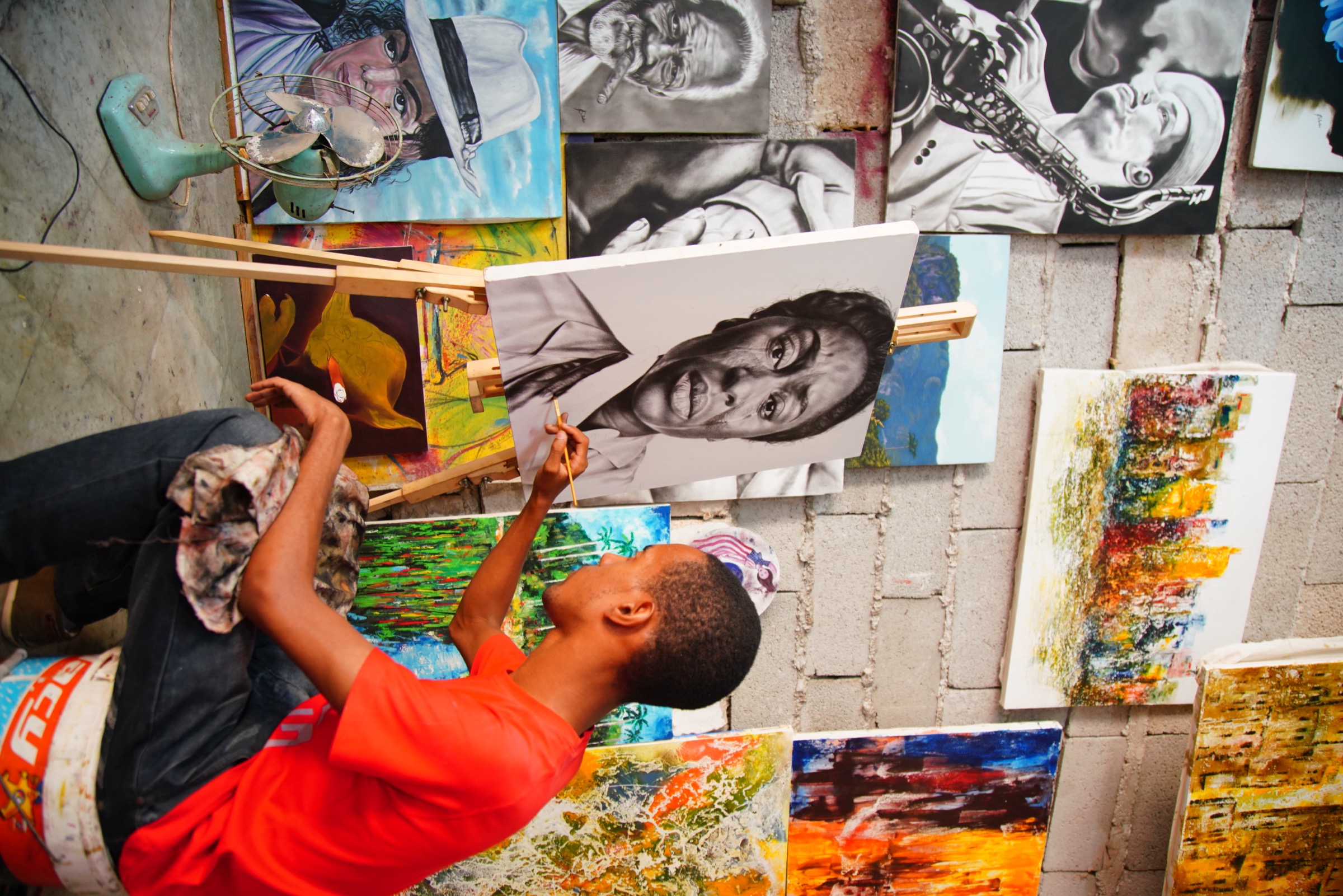 A young artist painting a portrait, surrounded by canvases