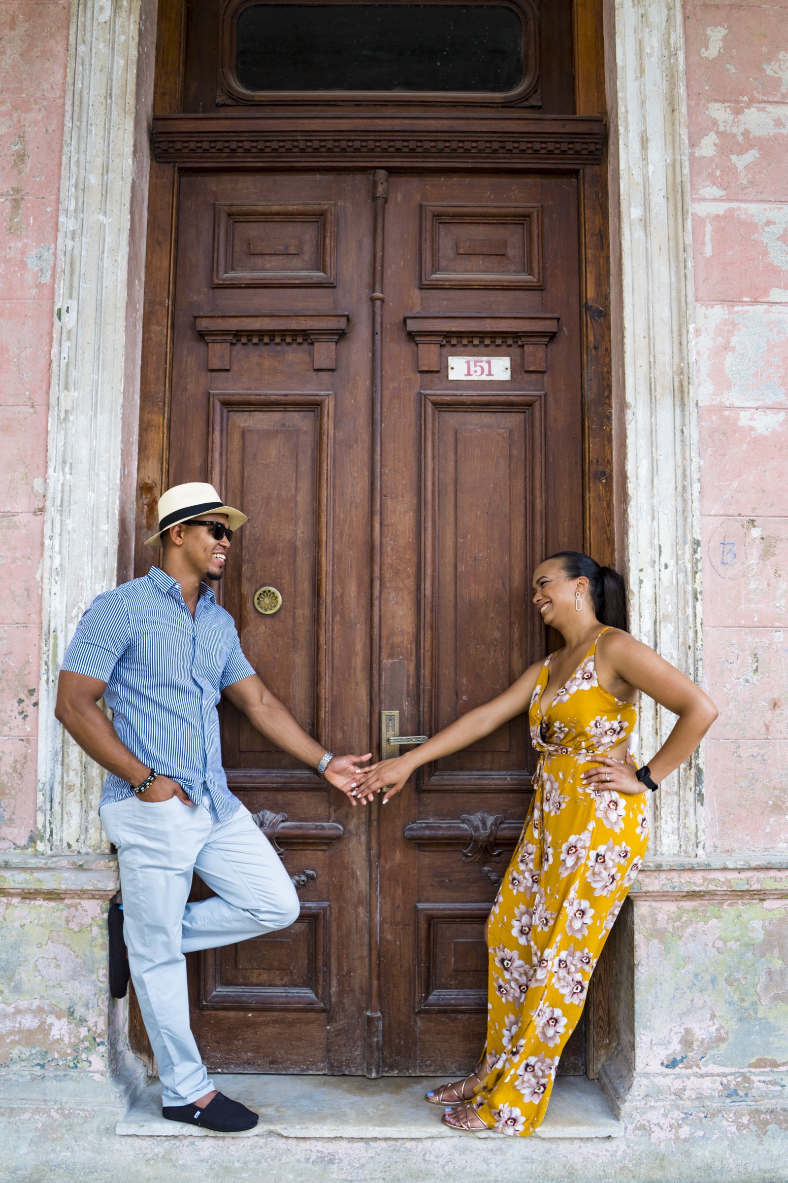 A couple at a tall ornate wooden door, number 151