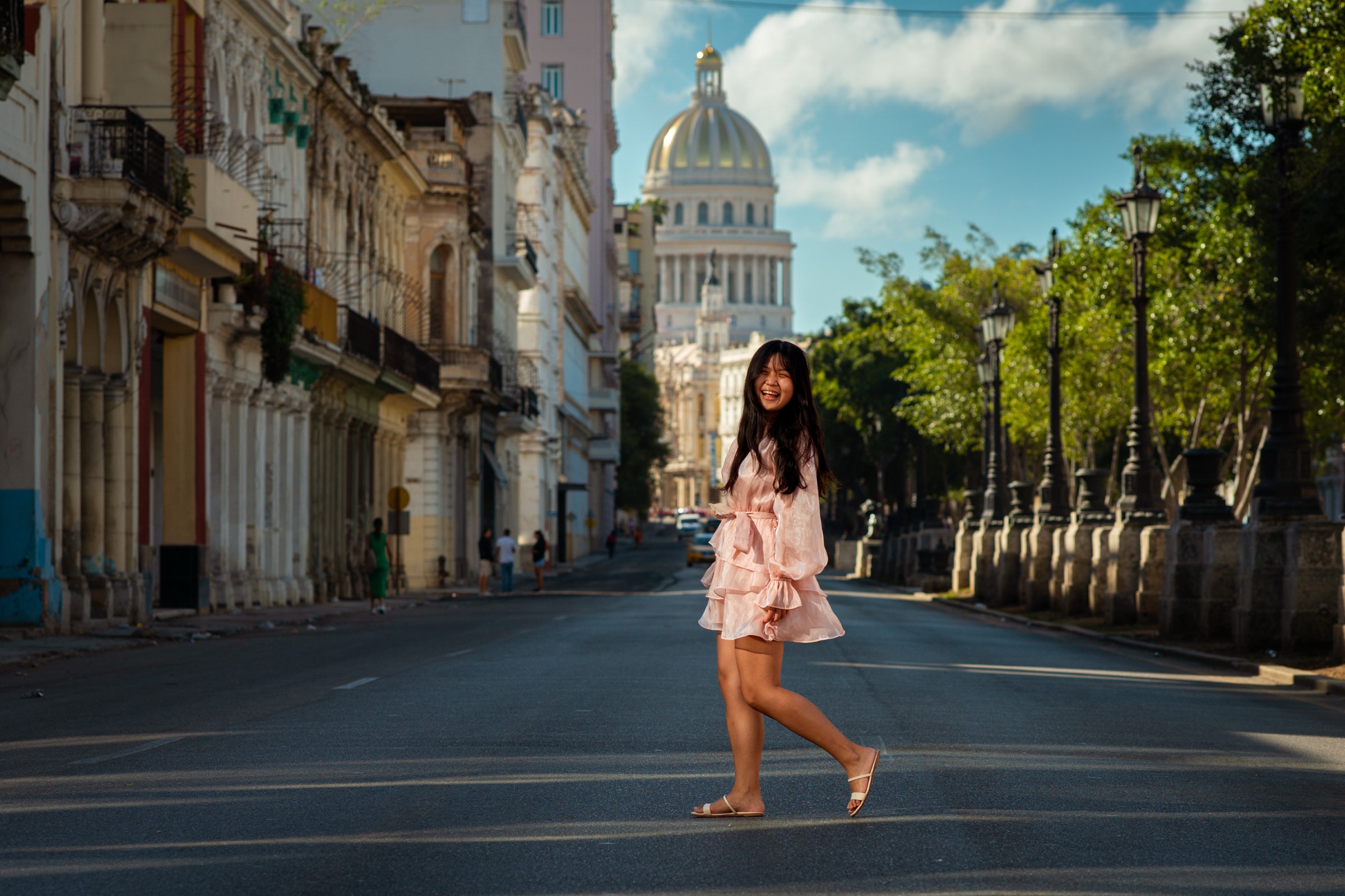 A woman standing in the empty boulevard, the Capitolio dome in the distance