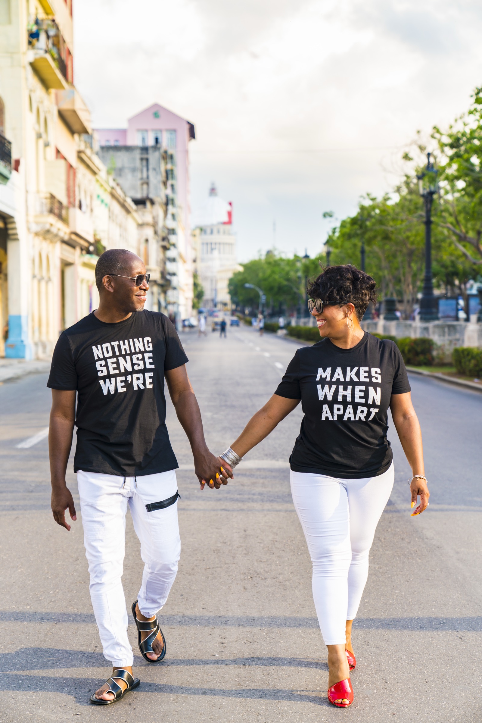 A couple walking hand in hand down the centre of the boulevard