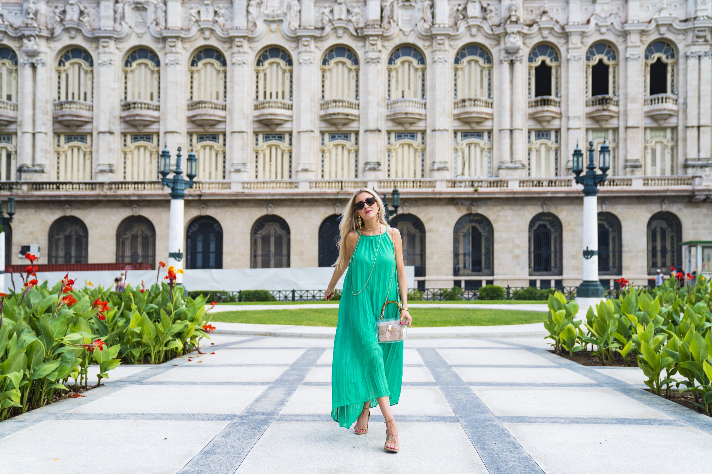 A woman walking the Capitolio's side garden, red flowers lining the path