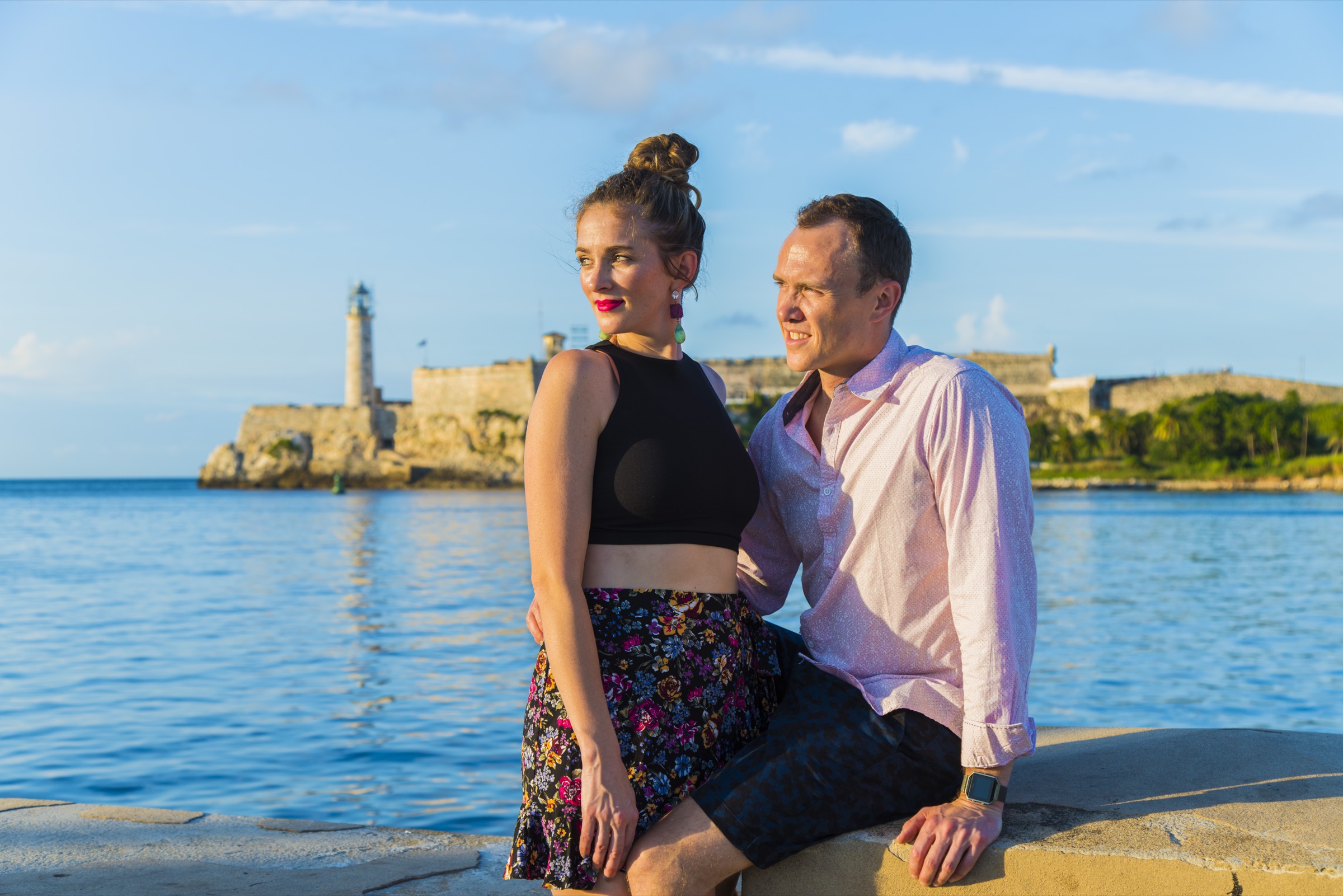A couple on the seawall at sunset, the Morro lighthouse across the water