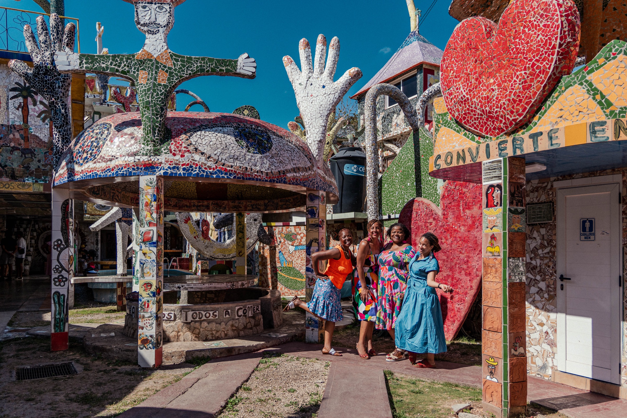A group of three by the heart and hands sculpture under blue sky