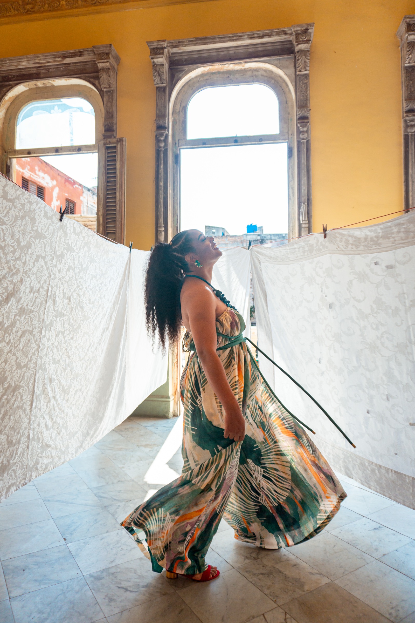 A woman in a flowing dress twirling between sheets of white lace hung to dry