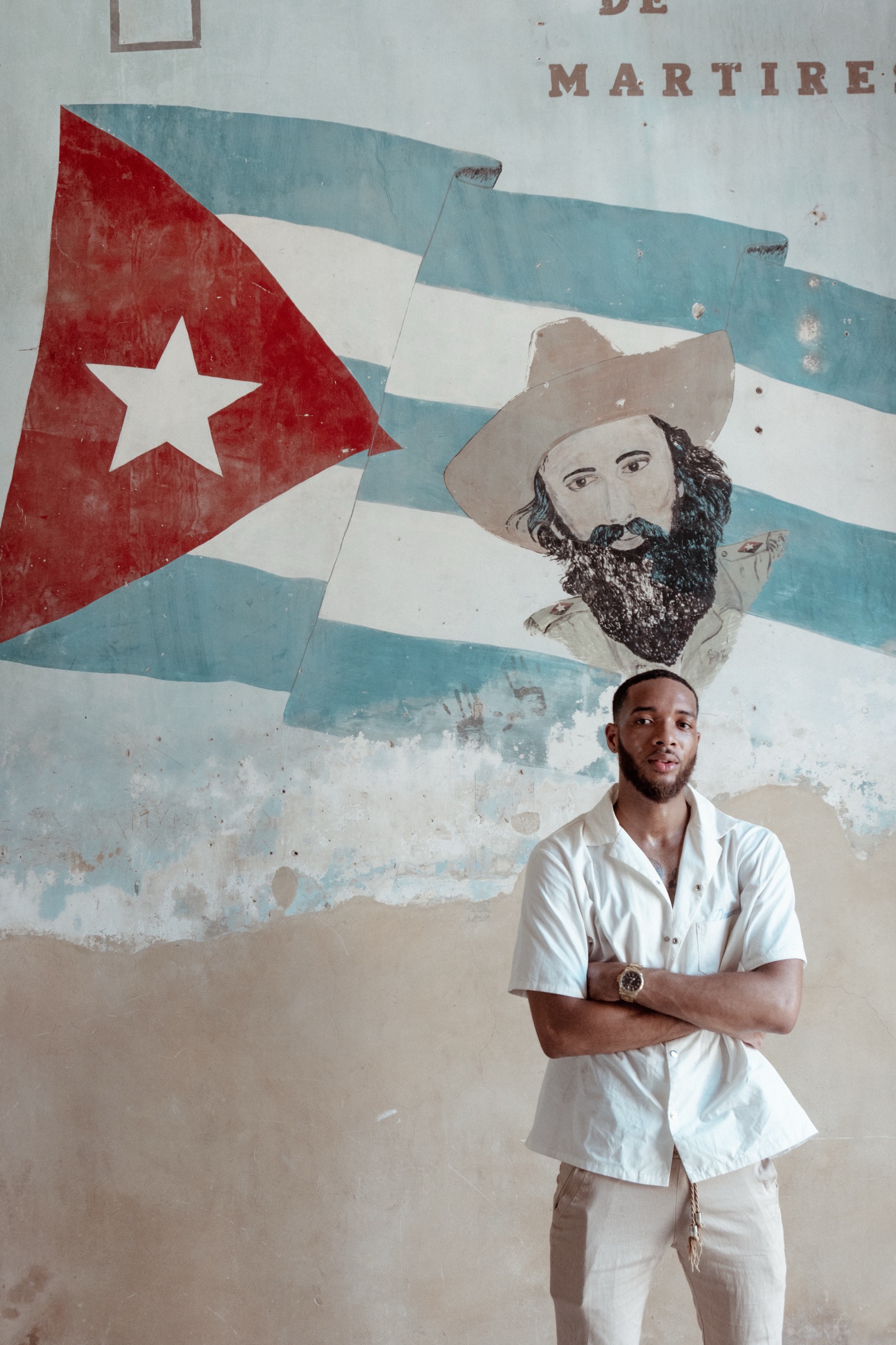 A man in white in front of the Cuban flag and martyrs mural on the stairwell