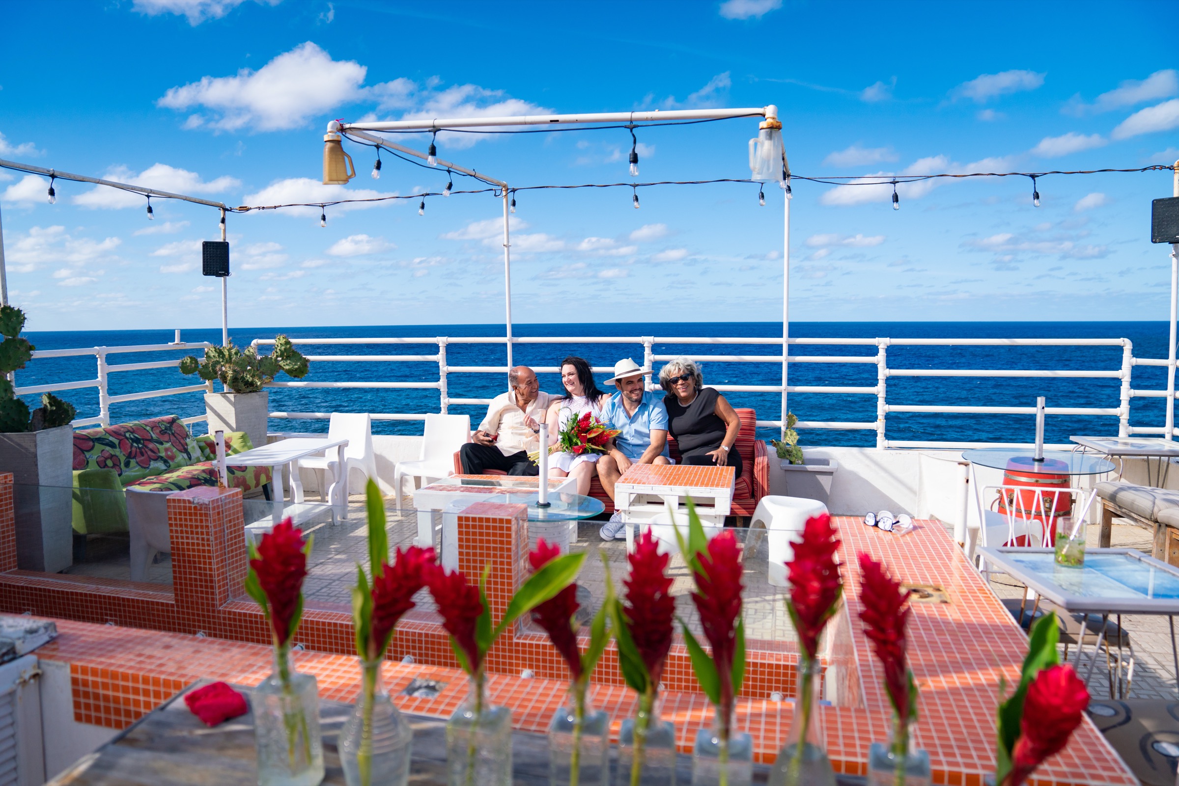 A group on the colorful rooftop terrace, the open sea stretching out behind