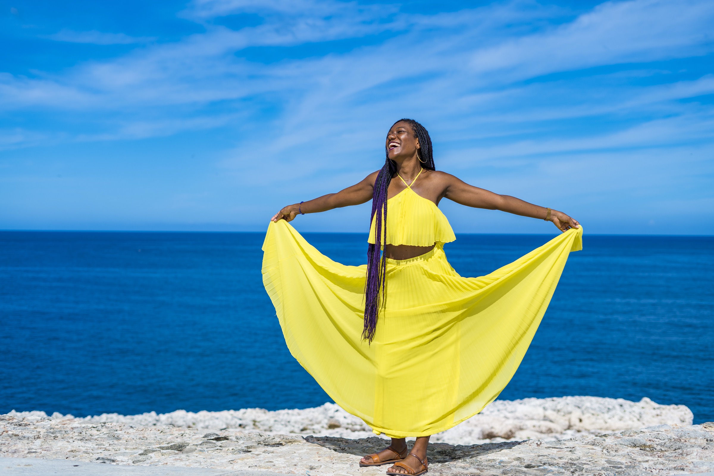 A woman in a yellow dress against deep blue ocean and sky