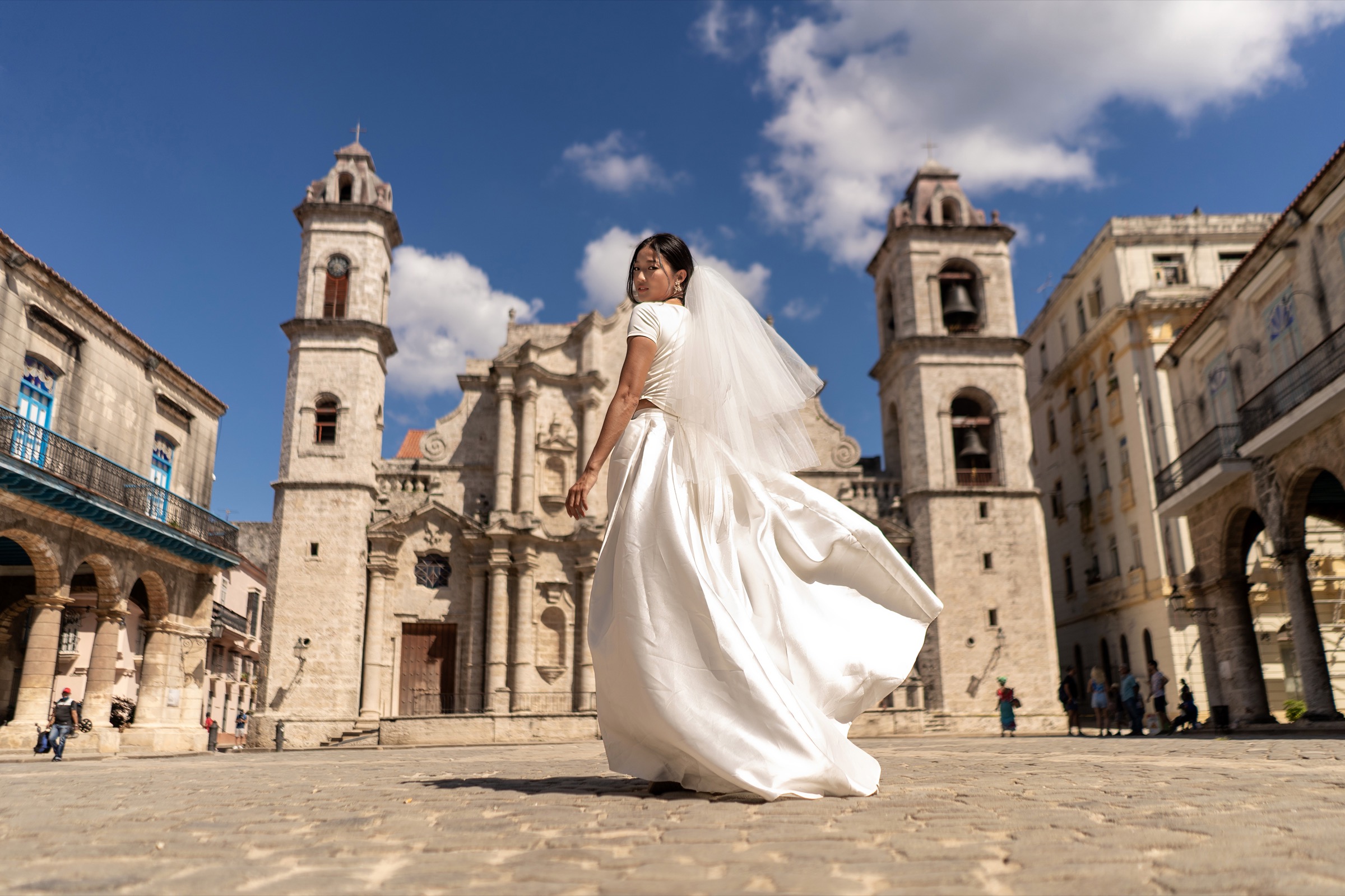 A bride in a white gown twirling in front of the cathedral's bell towers