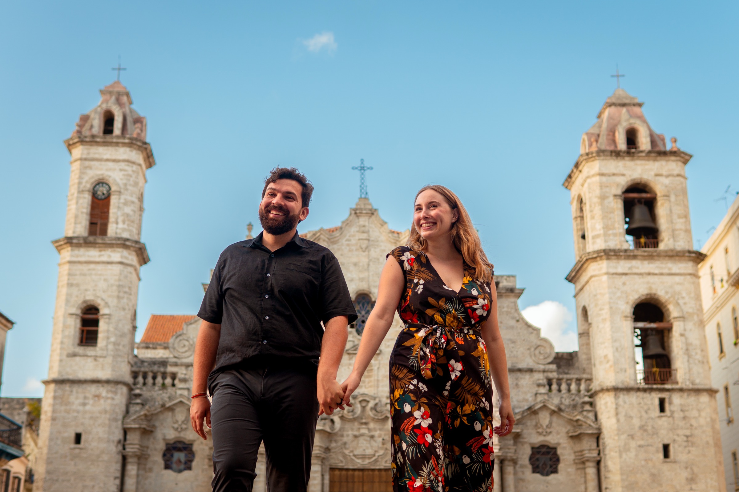A couple walking across the square, the cathedral's two towers behind