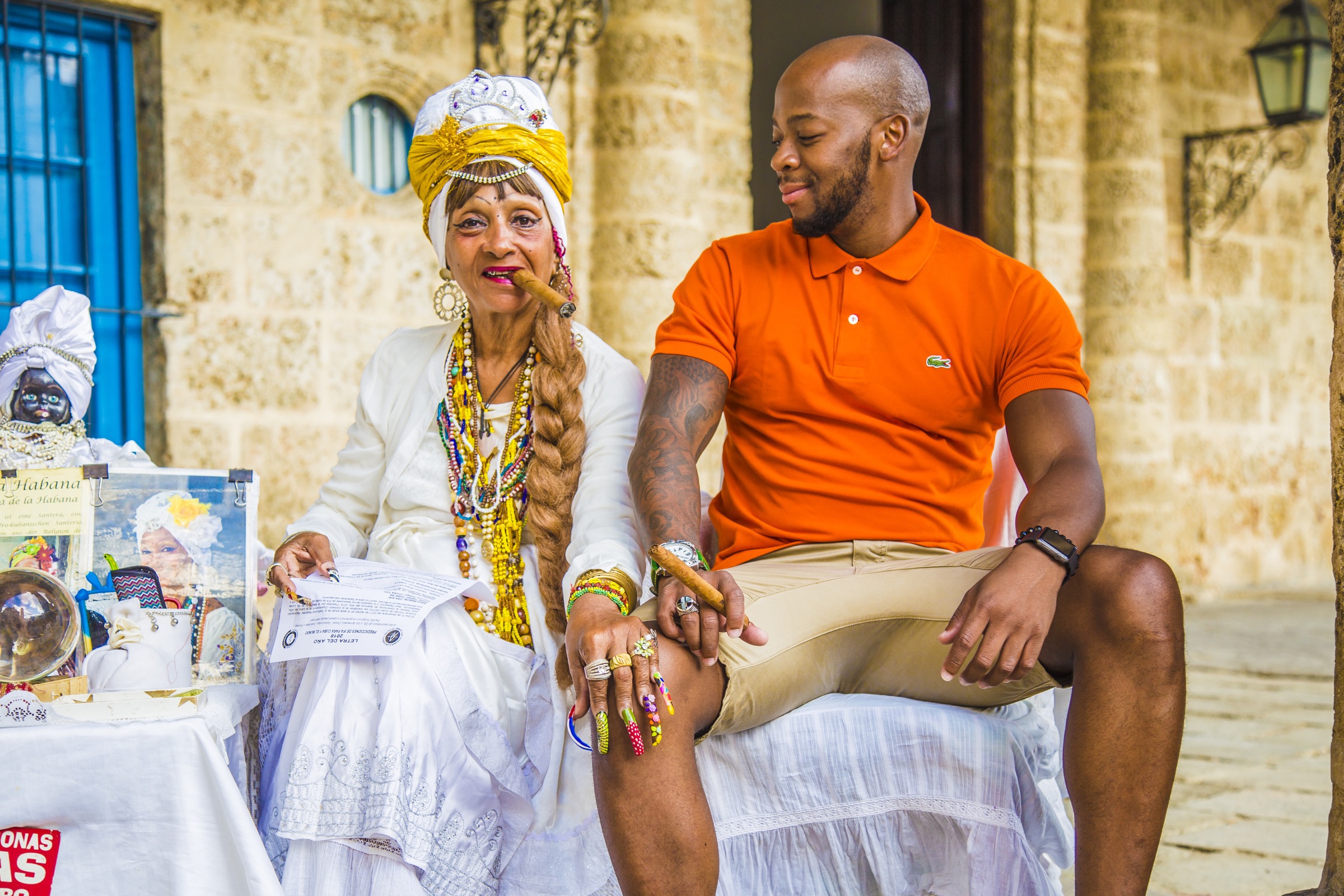 A guest beside a costumed fortune-teller with cards and a cigar