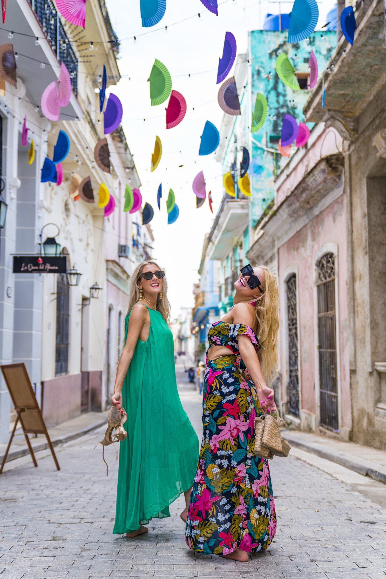 Two women under colourful paper fans strung across a lane