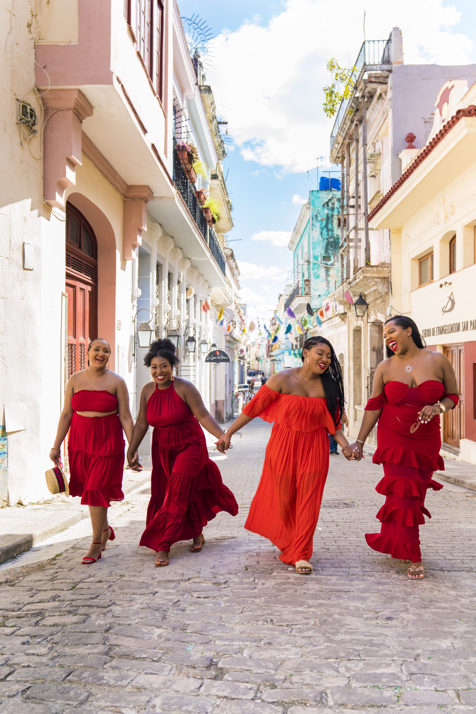 Four women in red dresses walking the cobbled rise